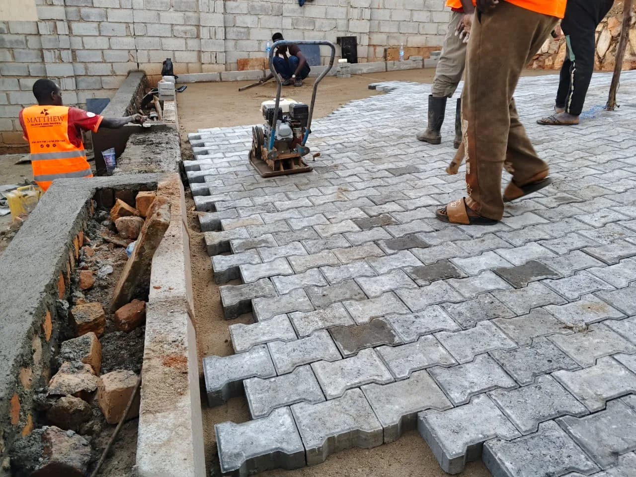 Paved driveway with a kerb line and pallets of pavers on site
